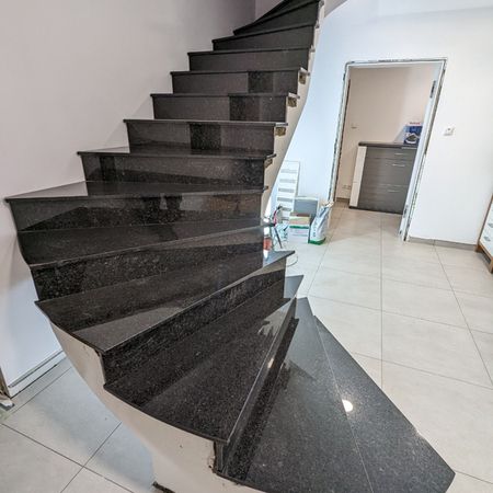 Schwarze Marmortreppe in einem eleganten Wohnhaus, die zu einem oberen Stockwerk führt.